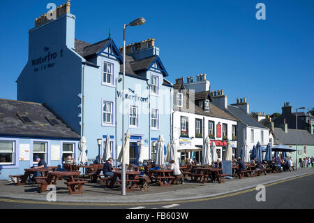 Menschen, die Getränke in der Sonne draußen The Waterfront Hotel und The Crown Hotel in Portpatrick genießen. Stockfoto