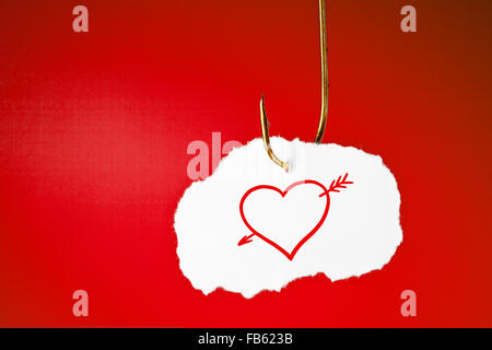 Ein Herz durchbohrt mit einem Pfeil auf weißes Blatt Papier hängen an einem Angelhaken auf rotem Hintergrund gezeichnet. Stockfoto