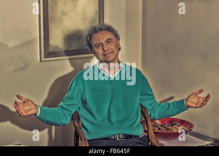 Mann mittleren Alters öffnet Arme winken beim Sitzen Stockfoto