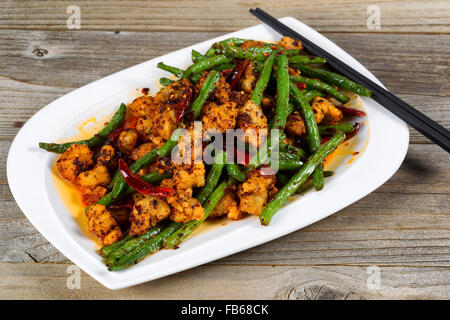 Nahaufnahme der knusprig gebratene Hähnchenteile mit grünen Bohnen und Chili Peppers auf rustikalen Holz Rahmen. Stockfoto