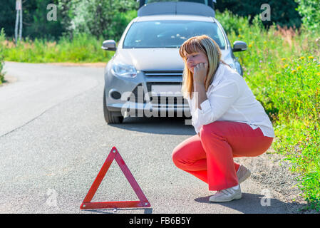 Frau auf der Straße in der Nähe von dem kaputten Auto umgekippt Stockfoto