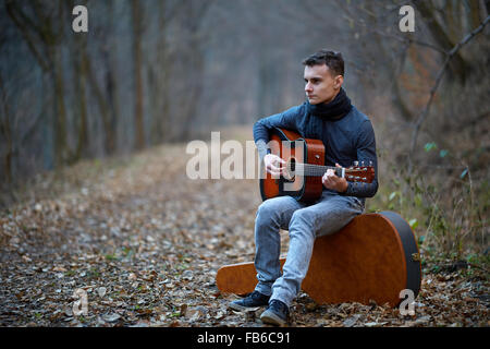 Teenager Gitarrist singen im Wald auf einer Gasse Stockfoto