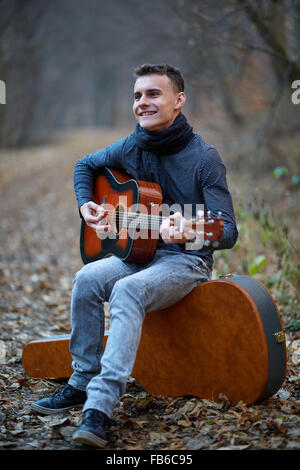 Teenager Gitarrist singen im Wald auf einer Gasse Stockfoto