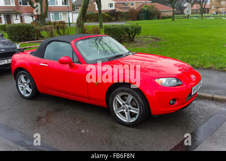 Eine helle rote 2006 registriert Mazda MX-3 soft Top Sportwagen im Regen geparkt Stockfoto