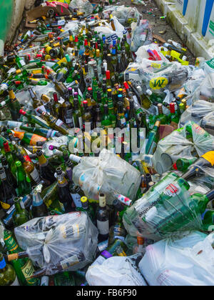 Recycling-Behälter für Mischglas über gefüllt und mit Flaschen gehäuft daneben nach Neujahrsfeiern Stockfoto