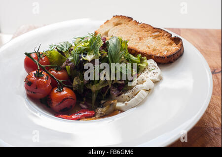 Eine italienische Antipasti-Teller einschließlich Bruschetta, gegrillten Cherry-Tomaten, Mozzarellakäse und Blätter. Stockfoto