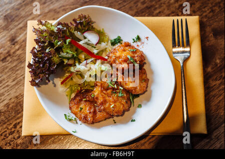 Indische Chicken Pakora, präsentiert auf einem weißen Teller und ruht auf einem gelben Serviette mit Gabel. Stockfoto