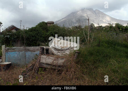 Sumatra, Indonesien. 11. Januar 2016. Eine Bank im Dorf Guruh Kinayan ist zwischen der linken Seite des zerstörten Hauses infolge eines Anstiegs der vulkanischen Rauch und Asche während der Eruption des Mount Sinabung, in Nord-Sumatra, Indonesien am 11. Januar 2016. Bildnachweis: Ivan Damanik/Alamy Live-Nachrichten Stockfoto