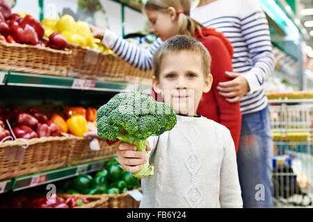 Junge zeigt Brokkoli im Supermarkt Stockfoto