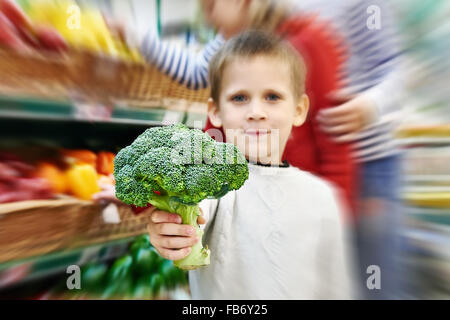 Junge zeigt Brokkoli im Supermarkt Stockfoto