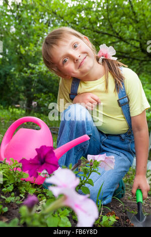 kleines Mädchen in die Federarbeit helfen im Garten Stockfoto