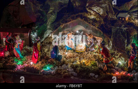 Statuen in eine Weihnachtskrippe, der seligen Jungfrau Maria und St. Joseph wachen über die Heiligen Jesuskind in einer Krippe in das Stroh wie der Ochse und der Esel sind Erwärmung, während die drei Könige bringen gaben Gold, Weihrauch und Myrrhe Stockfoto