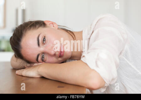 Junge Frau lehnt sich auf Tisch, Porträt Stockfoto