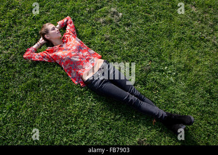 Junge Frau liegt auf dem Rasen im park Stockfoto