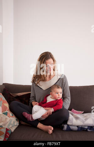 Frau mit Baby Girl auf Sofa zu Hause sitzen Stockfoto