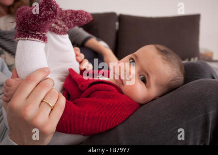 Seite Ansicht Porträt von niedlichen Babymädchen auf Vaters Schoß zu Hause Stockfoto