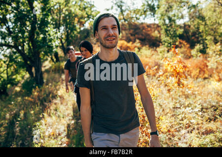 Lächelnd jungen Mann mit Freunden im Wald wandern Stockfoto