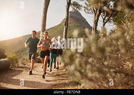 Gruppe von jungen Erwachsenen training und laufen gemeinsam durch Wanderwege am Hang im Freien in der Natur. Fit Jugendlichen trail ru Stockfoto