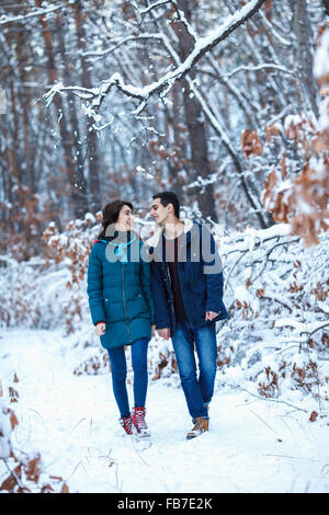 Volle Länge des jungen Liebespaar in warme Kleidung zu Fuß auf schneebedecktes Feld Stockfoto