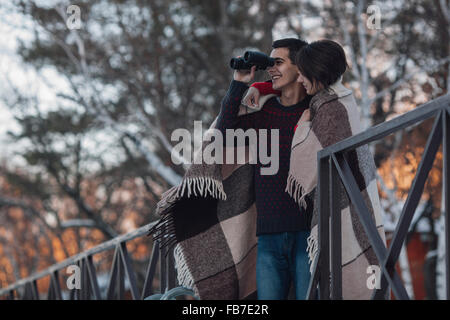 Junge Frau mit Mann, Blick durch ein Fernglas im winter Stockfoto