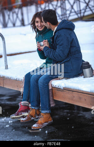 Volle Länge des jungen Brautpaares Kaffeetrinken am pier Stockfoto