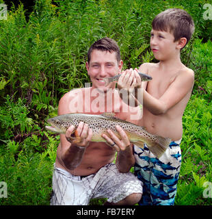 Vater und Sohn posiert mit Erwachsenen Forellen und Baby im Sommer Stockfoto