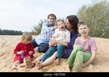 Fröhliche Familie Zusammensitzen auf Sanddüne Stockfoto