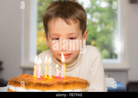 Niedlichen Geburtstagskind Blick auf Kerzen auf Kuchen Stockfoto