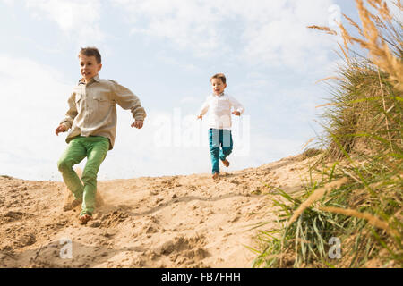 Niedrigen Winkel Ansicht der Brüder laufen auf Sand Düne Stockfoto