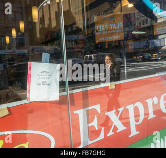 New York, USA. 11. Januar 2016. Ein Lotterie-Verkäufer hängt den Powerball Jackpot Ausdruck, $ 1,4 Milliarden so weit nach Powerball Beamten im Schaufenster seines Ladens auf Montag, 11. Januar 2016. Der Jackpot hat mehr als 18 Mal gerollt, ohne Sieger mit der nächsten Ziehung Mittwoch. Bildnachweis: Richard Levine/Alamy Live-Nachrichten Stockfoto