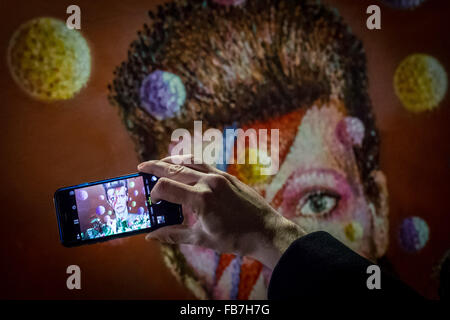 London, UK. 11. Januar 2016. Fans versammeln sich an David Bowie Wandbild in Brixton, Südlondon für einen Abend Erinnerung Vigil zu legen Blumen und Nachrichten hinterlassen. David Bowie (1947-2016), die verstarb am 10. Januar 2016 Credit: Guy Corbishley/Alamy Live News Stockfoto