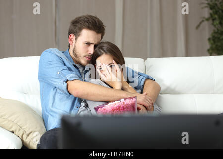 Paar zu beobachten und Terror TV-Film sitzt auf einer Couch zu Hause genießen Stockfoto