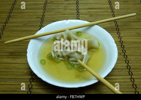 Won Ton Nudeln in Suppe Brühe mit Stäbchen auf Bambusmatte. Stockfoto