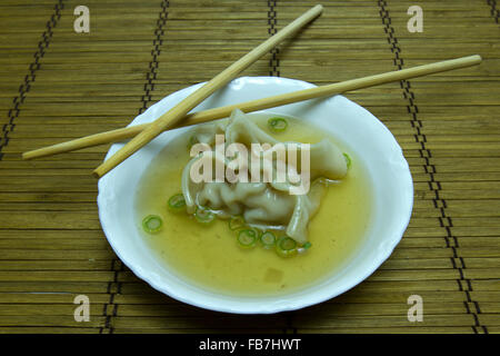 Won Ton Nudeln in Suppe Brühe mit Stäbchen auf Bambusmatte. Stockfoto