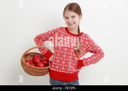 Smiley Kind trägt schöne rote Pullover und hält Weihnachtsdekoration Stockfoto