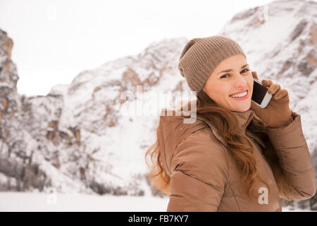 Energie-Füllung und aufregenden Winter-Wochenenden in den Bergen. Porträt der glückliche junge Frau Handy im Freien unter sn sprechen Stockfoto