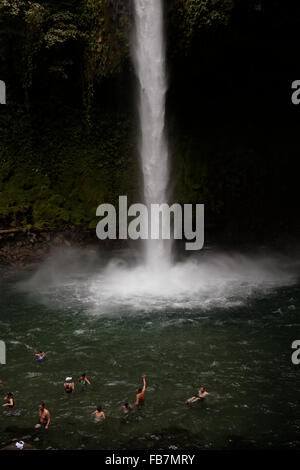 Menschen schwimmen in einem Pool am unteren Rand ein Wasserfall aus dem Dschungel in Nationalpark Vulkan Arenal in Costa Rica Stockfoto