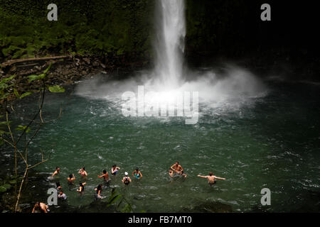 Menschen schwimmen in einem Pool am unteren Rand ein Wasserfall aus dem Dschungel in Nationalpark Vulkan Arenal in Costa Rica Stockfoto