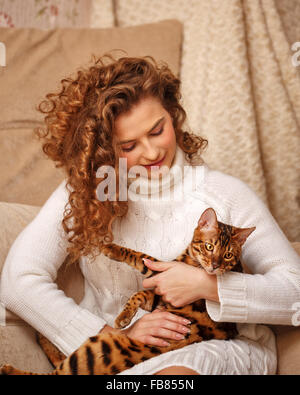 Mädchen und Leopard Katze nach Hause. Wohnkomfort. Mädchen umarmt Kat. Stockfoto