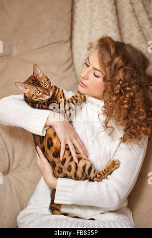 Mädchen und Bengal Katze nach Hause. Wohnkomfort. Mädchen umarmt Kat. Stockfoto