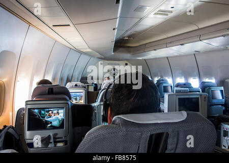 Passagiere in der Businessclass Kabine beobachten Entertainment Bildschirme Lufthansa 747 Flugzeug im Flug Stockfoto