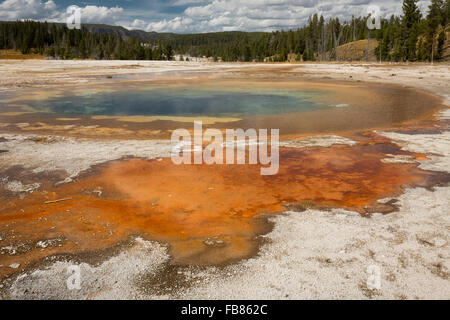 Bunte orange Wasser bei chromatischen Pool heißen Quellen unter einem sonnigen blauen Himmel im oberen Geysir-Becken von Yellowstone Park. Stockfoto