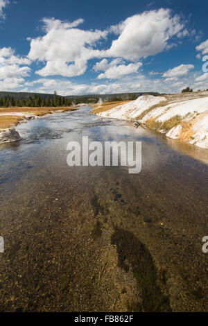 Firehole River fließt durch Kalkablagerungen des Upper Geyser Basin im Yellowstone National Park unter einem tiefblauen Himmel. Stockfoto