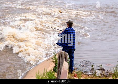 Ein Mann in den Fluten des Sees Hefner in Oklahoma City nach einem Frühlingsregen fischt. USA. Stockfoto