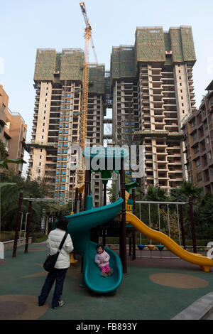 Ein Kleinkind spielt auf dem Spielplatz von einer gated Community, während der Komplex der Wohnungen weiterhin mit Highrise Wohn zu erweitern Stockfoto