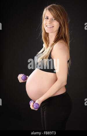 Schöne schwangere Frau, die das Training mit Hanteln Stockfoto