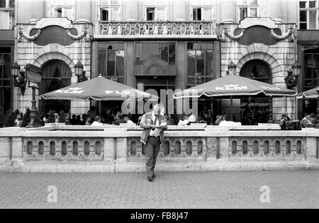 Blick auf Bupapest zum Zeitpunkt der neunziger Jahre. -1990 - Ungarn / Budapest - Blick auf Bupapest zum Zeitpunkt der neunziger Jahre. -Alltägliche Szene. Ein Mann liest ein Buch am Eingang der u-Bahnstation "Foldalatti"; in der Zwischenzeit einige Touristen und Ungarn sitzen Oustide eines großen Restaurants von der quadratischen Hosok Tere (Heldenplatz) - Philippe Gras / Le Pictorium Stockfoto