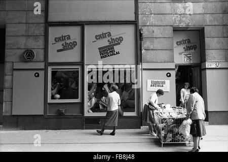 Blick auf Bupapest zum Zeitpunkt der neunziger Jahre. -1990 - Ungarn / Budapest - Blick auf Bupapest zum Zeitpunkt der neunziger Jahre. -Alltägliche Szene. Ein Frauen-Fashion-Store. Eine ungarische Frau sucht das Schaufenster während zwei andere suchen in zwei große Körbe.    -Philippe Gras / Le Pictorium Stockfoto