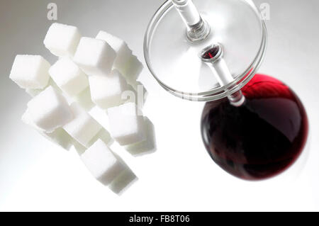 weißer granulierter Zuckerwürfel und ein Glas Rotwein Stockfoto