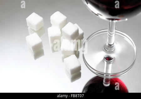 weißer granulierter Zuckerwürfel und ein Glas Rotwein Stockfoto